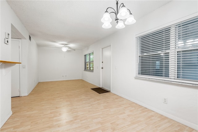 unfurnished room with ceiling fan with notable chandelier, a textured ceiling, and light hardwood / wood-style flooring