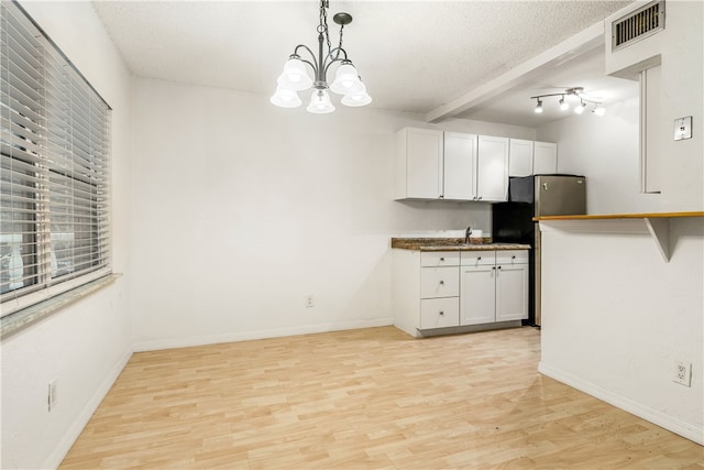 kitchen featuring beamed ceiling, white cabinetry, hanging light fixtures, and light wood-type flooring