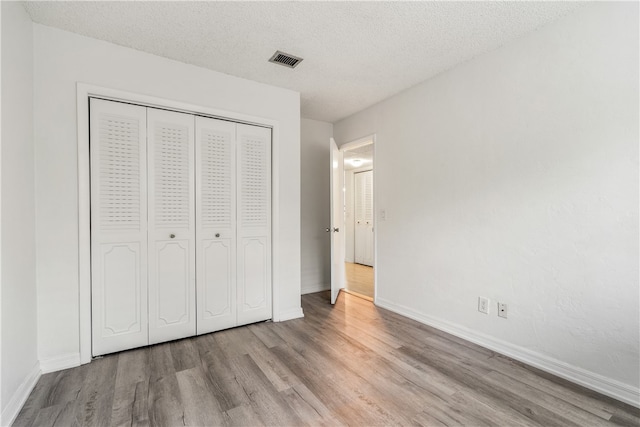 unfurnished bedroom with a closet, a textured ceiling, and light hardwood / wood-style floors