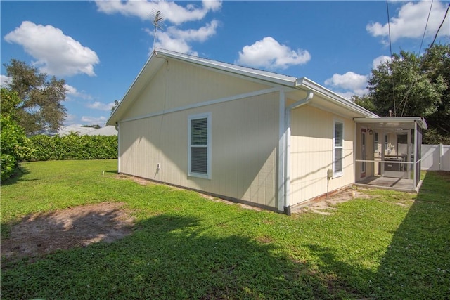 view of side of home with a sunroom and a lawn