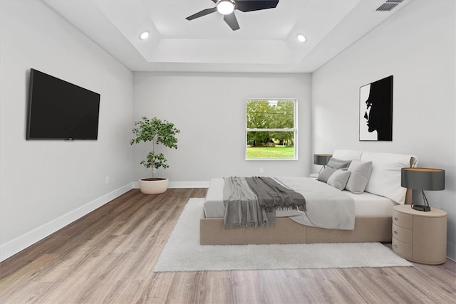 unfurnished bedroom featuring a raised ceiling, ceiling fan, and light hardwood / wood-style flooring