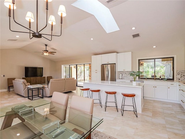 dining space featuring ceiling fan, vaulted ceiling with skylight, and a wealth of natural light