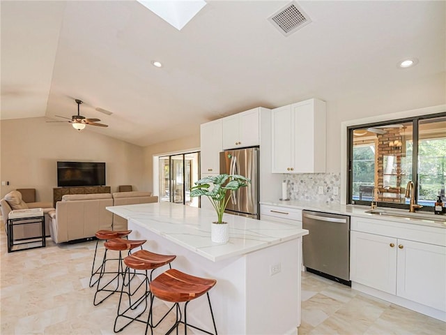 kitchen with sink, a breakfast bar area, white cabinetry, a center island, and stainless steel appliances