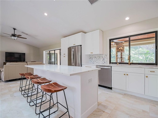 kitchen featuring white cabinetry, sink, a center island, light stone counters, and stainless steel appliances