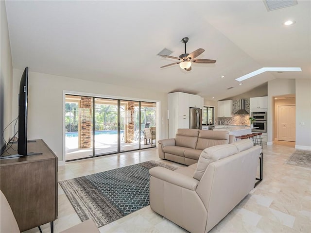 living room with ceiling fan and lofted ceiling with skylight