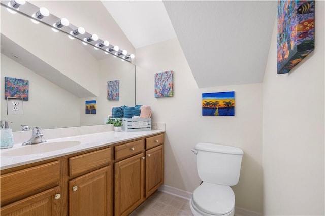 bathroom with lofted ceiling, baseboards, vanity, and toilet