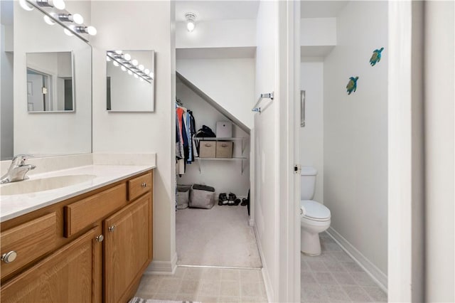 bathroom with toilet, vanity, and baseboards