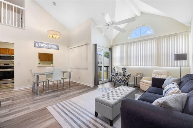 living room with high vaulted ceiling, light wood finished floors, a ceiling fan, baseboards, and beam ceiling