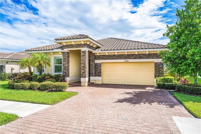 view of front of house featuring stucco siding, a garage, stone siding, a tile roof, and decorative driveway