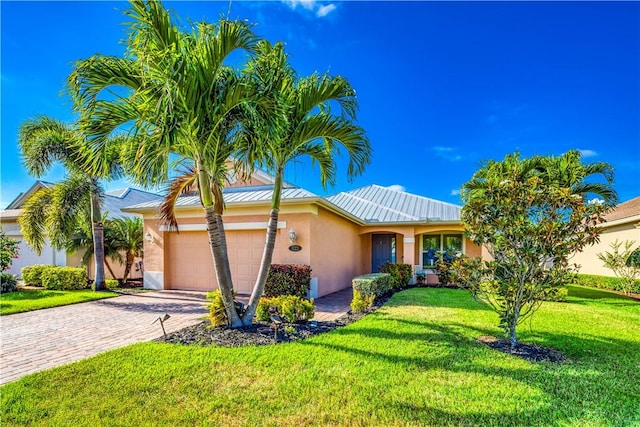 1122 4th Ln SW, Vero Beach, FL 32962 - ranch-style house with stucco siding, an attached garage, a front yard, decorative driveway, and a standing seam roof