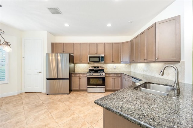 1122 4th Ln SW, Vero Beach, FL 32962 - kitchen featuring stainless steel appliances, a sink, dark stone countertops, backsplash, and light tile patterned floors
