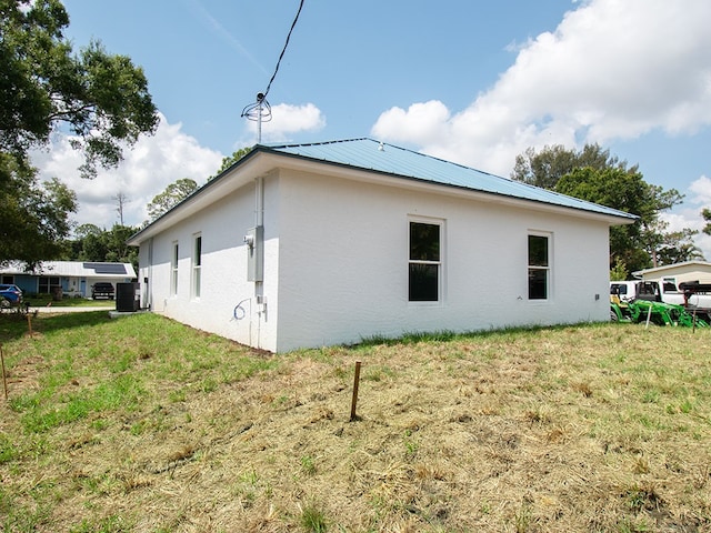 6156 6th Pl, Vero Beach, FL 32968 - view of side of property with stucco siding, a yard, central air condition unit, and metal roof