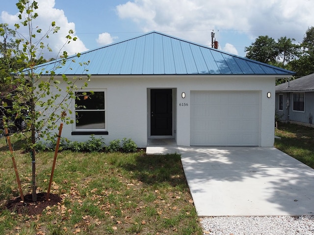 6156 6th Pl, Vero Beach, FL 32968 - view of front of home with stucco siding, a standing seam roof, an attached garage, concrete driveway, and metal roof