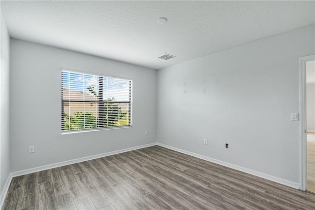 spare room featuring hardwood / wood-style floors and a textured ceiling