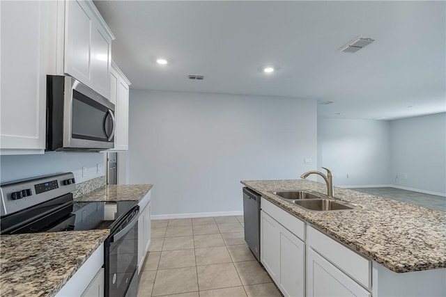 kitchen with sink, white cabinetry, stainless steel appliances, light stone counters, and an island with sink