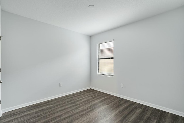 unfurnished room with dark wood-type flooring