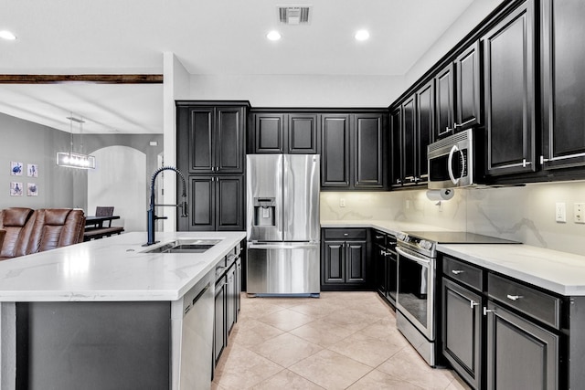 kitchen featuring decorative light fixtures, stainless steel appliances, a center island with sink, and sink