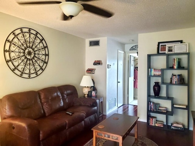 living room featuring ceiling fan, dark hardwood / wood-style floors, and a textured ceiling