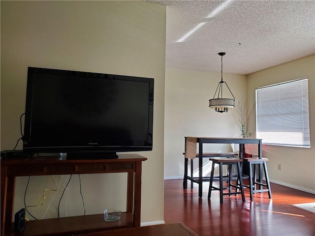 dining space with a textured ceiling, wood finished floors, and baseboards