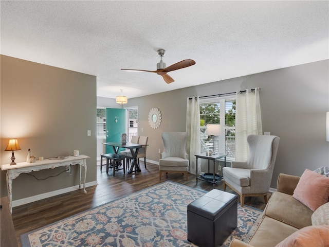 living room with a textured ceiling, dark hardwood / wood-style flooring, and ceiling fan