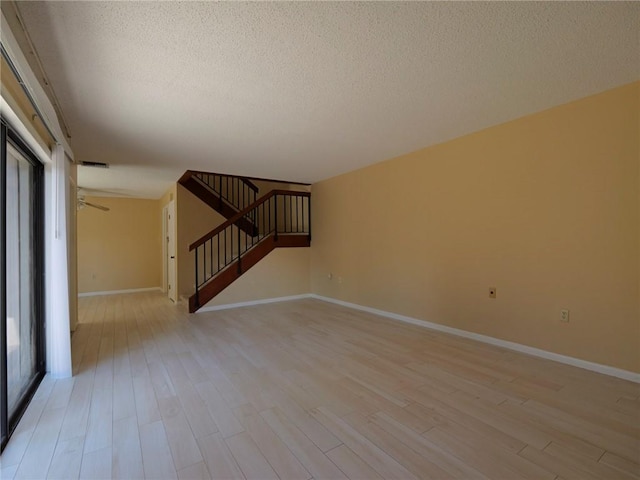 unfurnished living room with light hardwood / wood-style flooring and a textured ceiling