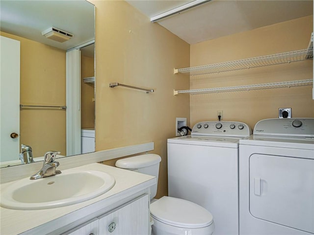 bathroom featuring vanity, washer and dryer, and toilet