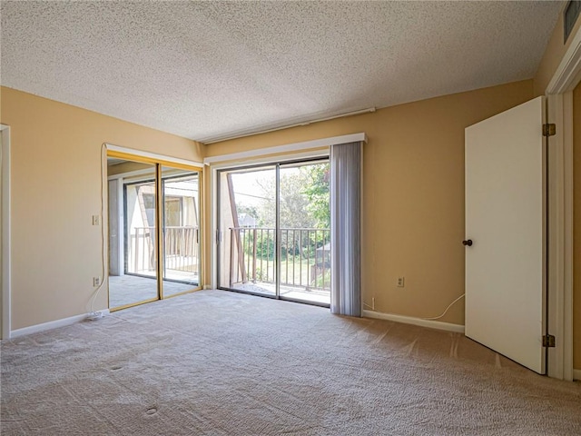 spare room featuring light colored carpet and a textured ceiling