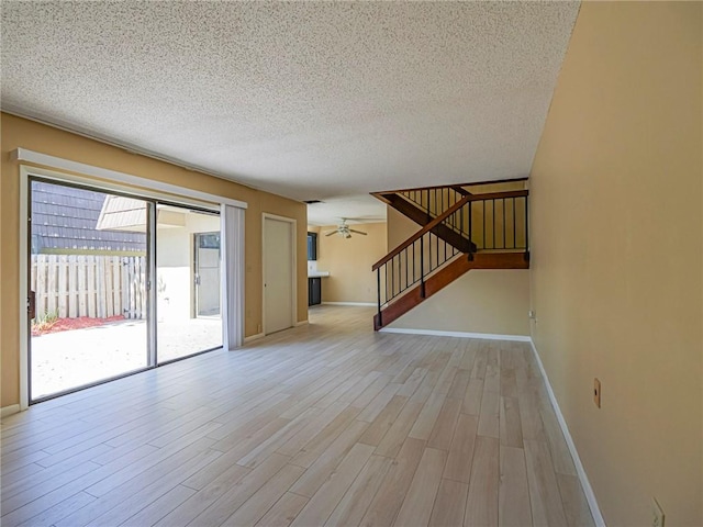 empty room with ceiling fan, light hardwood / wood-style flooring, and a textured ceiling