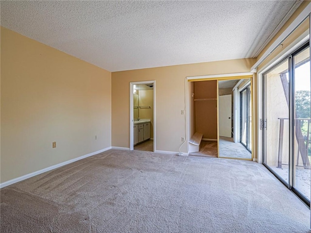 unfurnished bedroom featuring light carpet, access to exterior, ensuite bath, and a textured ceiling