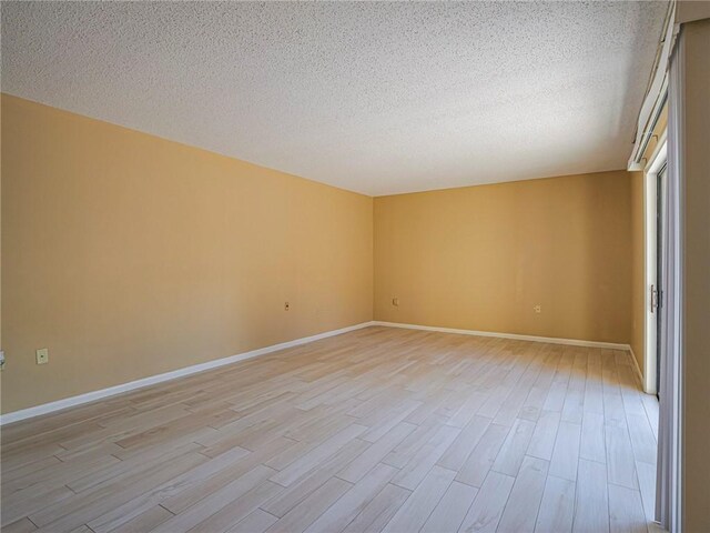 spare room featuring a textured ceiling and light wood-type flooring