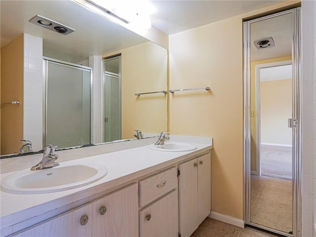 bathroom with a shower with door, vanity, and tile patterned floors