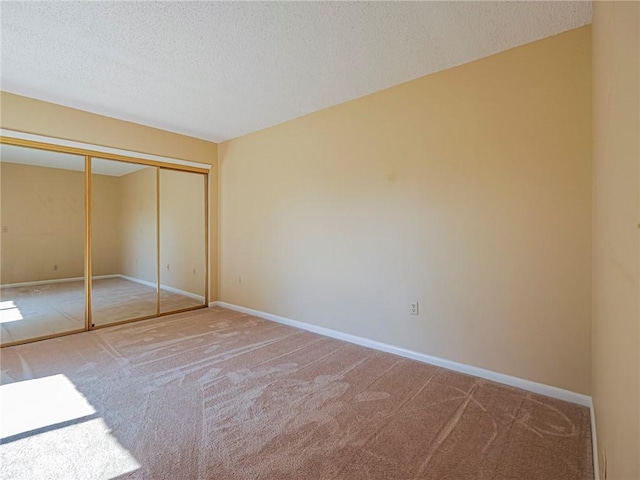 unfurnished bedroom with carpet floors, a textured ceiling, and a closet