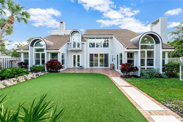 back of property featuring french doors, a yard, and a balcony