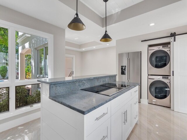 8405 Red Bay Ct Unit 8405, Vero Beach, FL 32963 - kitchen featuring white cabinets, a barn door, black electric cooktop, stacked washer / drying machine, and high end fridge