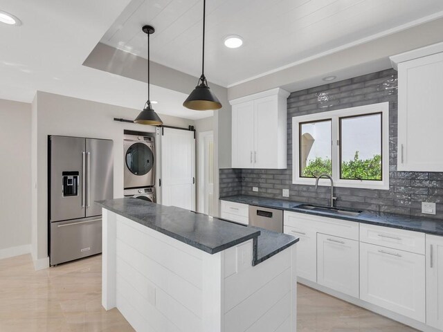 8405 Red Bay Ct Unit 8405, Vero Beach, FL 32963 - kitchen featuring a kitchen island, stacked washer / dryer, appliances with stainless steel finishes, a sink, and backsplash