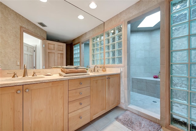 bathroom featuring tile patterned flooring, a tile shower, vanity, and tile walls