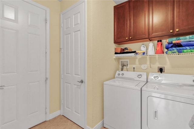 laundry area with washer and dryer, light tile patterned floors, and cabinets