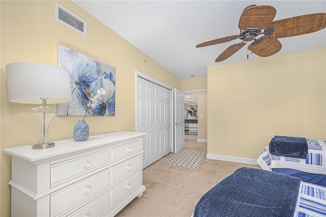 living area featuring a textured ceiling, ceiling fan, light tile patterned flooring, visible vents, and baseboards