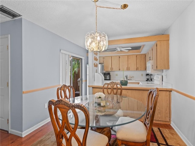 dining room featuring hardwood / wood-style flooring, sink, ceiling fan with notable chandelier, and a textured ceiling