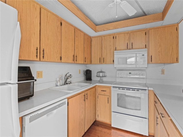 kitchen featuring a raised ceiling, sink, white appliances, and light wood-type flooring