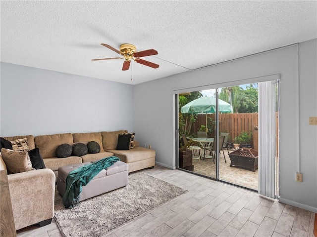 living room with ceiling fan, light hardwood / wood-style floors, and a textured ceiling