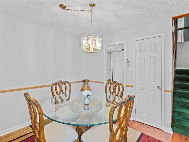 dining room featuring a chandelier, light hardwood / wood-style flooring, and a textured ceiling