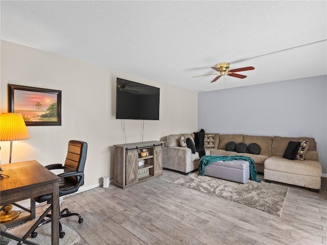 living room with a textured ceiling, ceiling fan, and light hardwood / wood-style flooring