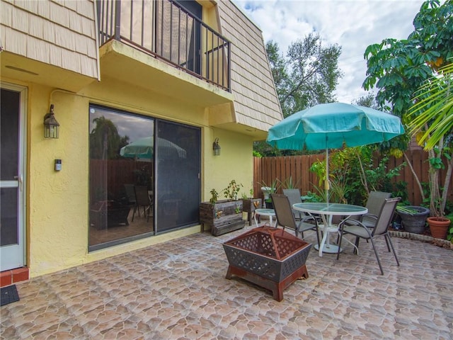 view of patio featuring a balcony and an outdoor fire pit