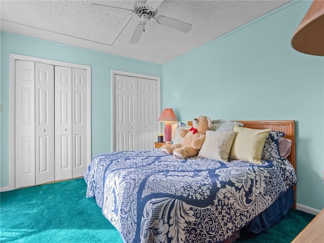 carpeted bedroom with ceiling fan, a textured ceiling, and multiple closets