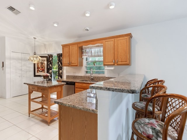 kitchen featuring kitchen peninsula, stone countertops, pendant lighting, stainless steel dishwasher, and sink