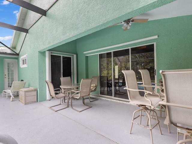 view of patio with ceiling fan and glass enclosure