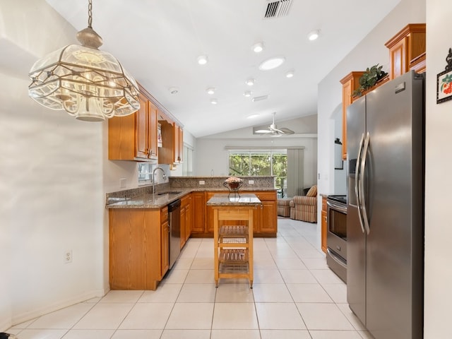 kitchen featuring ceiling fan, vaulted ceiling, dark stone countertops, a center island, and stainless steel appliances