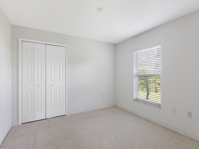 unfurnished bedroom featuring a closet and light colored carpet