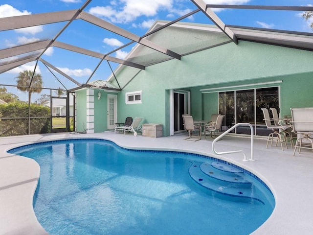 view of pool with glass enclosure and a patio area